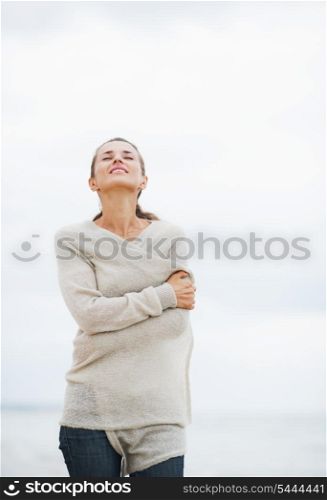 Relaxed young woman in sweater walking on lonely beach