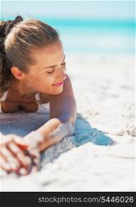 Relaxed young woman in swimsuit laying on beach