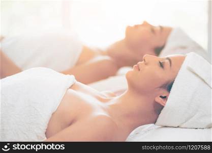 Relaxed young woman lying on spa bed prepared for facial treatment and massage in luxury spa resort. Wellness, stress relief and rejuvenation concept.
