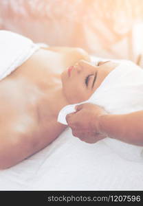 Relaxed young woman lying on spa bed prepared for facial treatment and massage in luxury spa resort. Wellness, stress relief and rejuvenation concept.