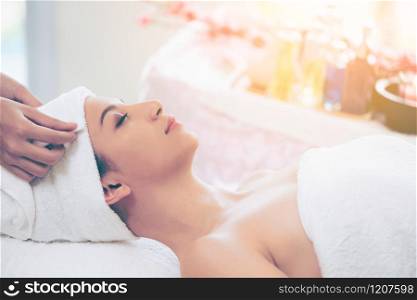 Relaxed young woman lying on spa bed prepared for facial treatment and massage in luxury spa resort. Wellness, stress relief and rejuvenation concept.