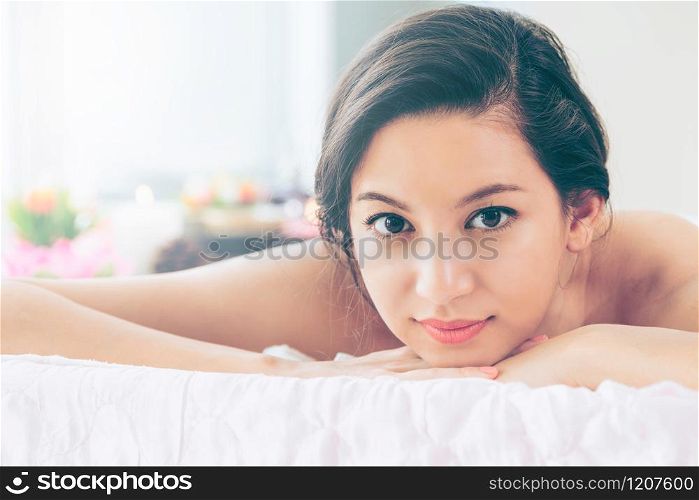 Relaxed young woman lying on spa bed prepared for massage treatment in luxury spa resort. Wellness, stress relief and rejuvenation concept.