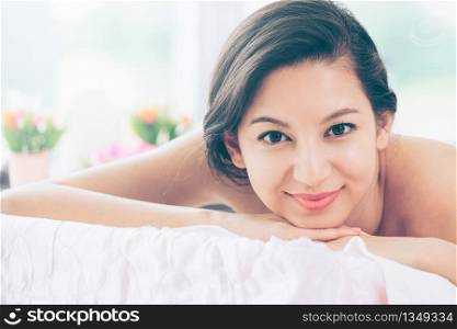Relaxed young woman lying on spa bed prepared for massage treatment in luxury spa resort. Wellness, stress relief and rejuvenation concept.