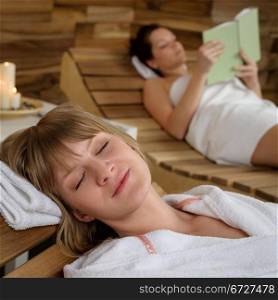 Relaxed young woman resting on wooden chair at luxury spa