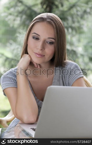 Relaxed young woman using laptop outdoors