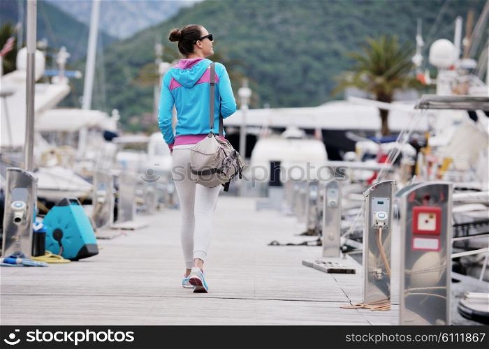 relaxed young woman walking in marina with yacht boats in bacground
