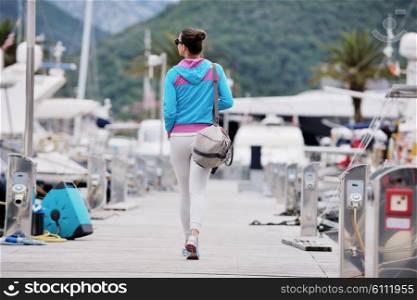 relaxed young woman walking in marina with yacht boats in bacground