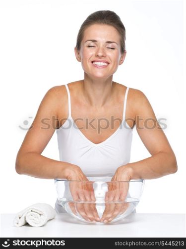 Relaxed young woman washing hands in glass bowl with water