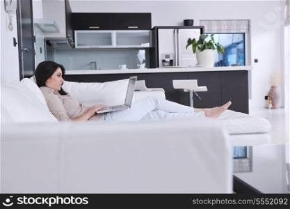 relaxed young woman working on laptop computer in bright home indoor