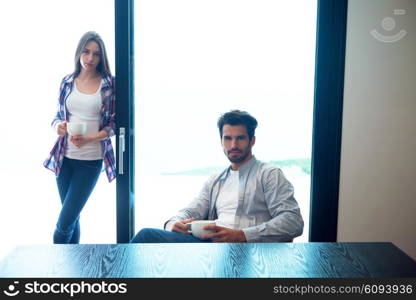 relaxet young couple drink first morning coffee over big bright window in moder home villa interior