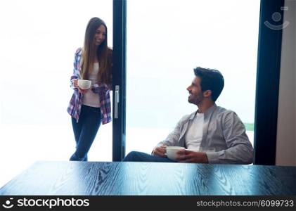 relaxet young couple drink first morning coffee over big bright window in moder home villa interior