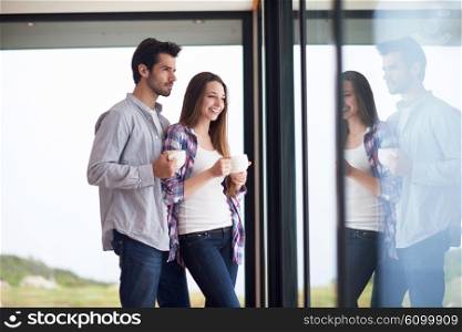 relaxet young couple drink first morning coffee over big bright window in moder home villa interior