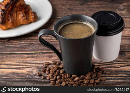 Relaxing americano coffee in black porcelain cup and take away cup on wooden table