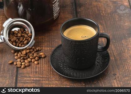 Relaxing americano coffee in black porcelain cup on wooden table