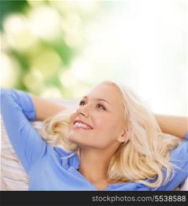 relaxing and happiness concept - smiling young woman lying on sofa