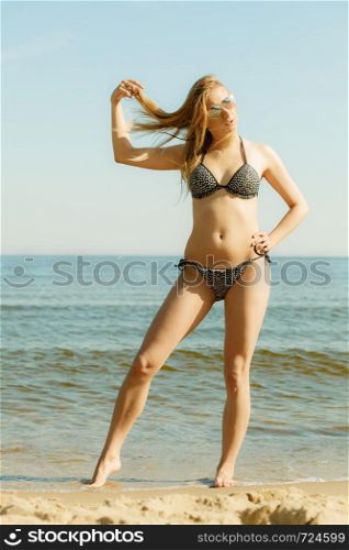 Relaxing during summertime, traveling, vacation concept. Woman in summer bikini walking on beach near sea, beautiful sunny weather.. Woman in bikini walking on beach