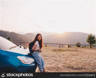 Relaxing in nature concept from Asian young woman traveler parking the car enjoy beautiful scenery of mountain landscape during sunset time. Woman tourist travel by car for road trip in Thailand.