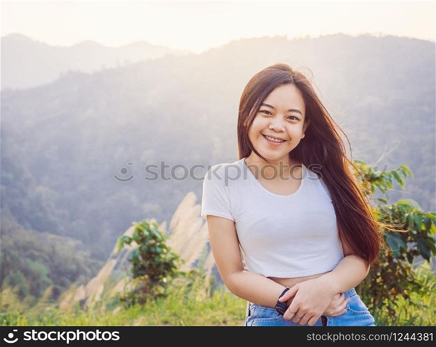 Relaxing in nature concept from hipster girl is happy and looking at camera with valley landscape view on peak mountains in tropical rain forest.