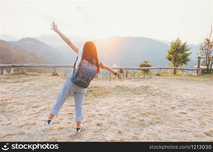 Relaxing in Nature concept from hipster girl with backpack that is smiling, cheerful and happy with atmosphere of autumn sunset on hills.