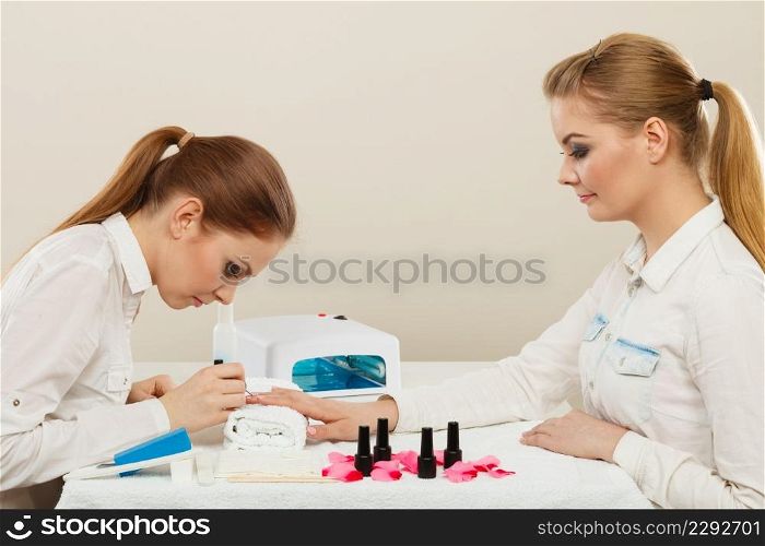 Relaxing time and wellness day concept. Blonde elegant woman visiting professional manicurist salon. Beautician makes perfect nails to client.. Beautician with client at beauty salon.