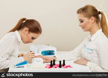 Relaxing time and wellness day concept. Blonde elegant woman visiting professional manicurist salon. Beautician makes perfect nails to client.. Beautician with client at beauty salon.