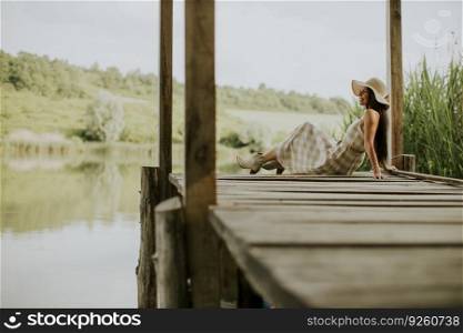 relaxing young woman on wooden pier at the calm lake