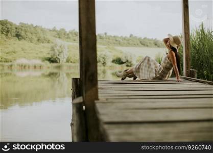 relaxing young woman on wooden pier at the calm lake