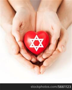 religion, christianity and charity concept - family couple hands holding red heart with star of david symbol