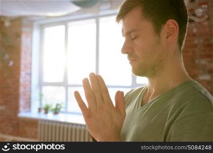 religion, faith and people concept - close up of woman meditating or praying at yoga studio. close up of man meditating at yoga studio. close up of man meditating at yoga studio