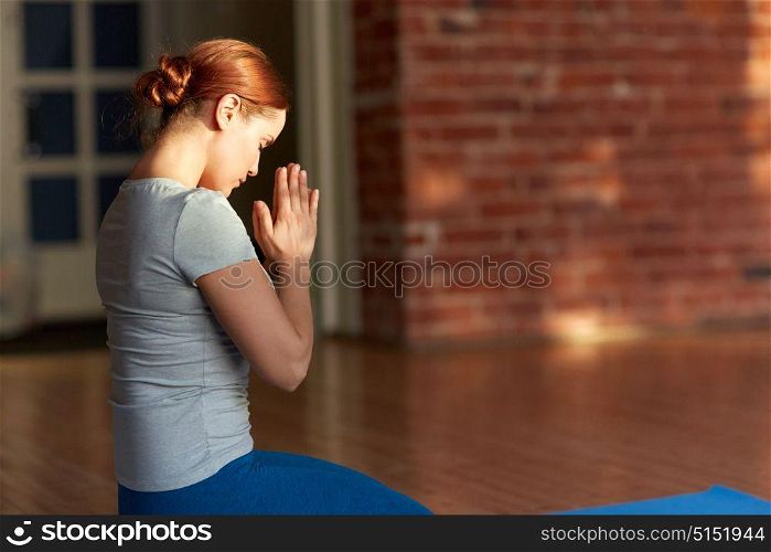 religion, faith and people concept - woman meditating at yoga studio. woman meditating at yoga studio