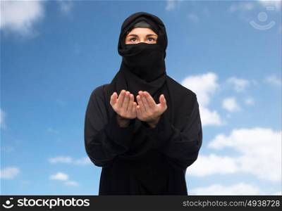 religion, faith, islam and people concept - praying muslim woman in hijab over blue sky and clouds background. praying muslim woman in hijab over white