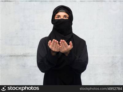 religion, faith, islam and people concept - praying muslim woman in hijab over gray concrete wall background. praying muslim woman in hijab over white
