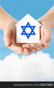religion, judaism and charity concept - close up of woman hands holding house with star of david over blue sky with white cloud background