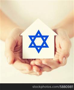 religion, judaism and charity concept - female hands holding paper house with star of david symbol