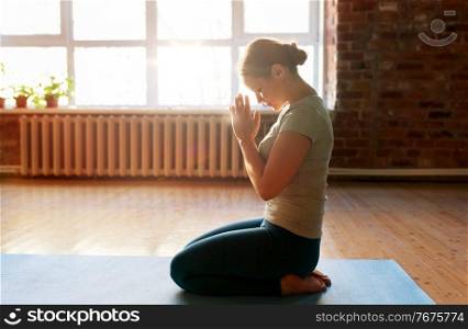 religion, meditation and people concept - close up of woman meditating at yoga studio or praying. close up of woman meditating at yoga studio