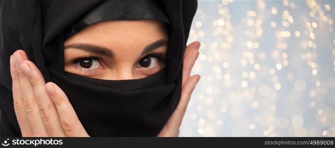 religious and people concept - close up of muslim woman in hijab over holidays lights background. close up of muslim woman in hijab
