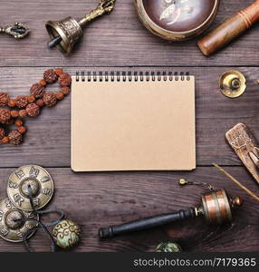 religious musical instruments for meditation and alternative medicine, blank notebook with brown sheets on a wooden background, top view, flat lay