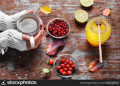 remedy from berries and honey. Cup in hand with autumn berry tea and jar of honey