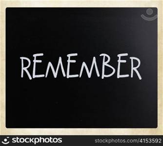 ""Remember" handwritten with white chalk on a blackboard"