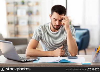 remote job and business concept - stressed man with papers, calculator and laptop computer working at home office. man with files and calculator works at home office