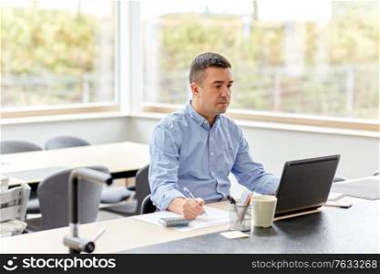 remote job, business and people concept - middle-aged man with calculator, papers and laptop computer working at home office. man with calculator and papers working at home