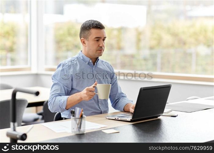 remote job, business and people concept - middle-aged man with laptop computer working at home office and drinking coffee. man with laptop drinking coffee at home office