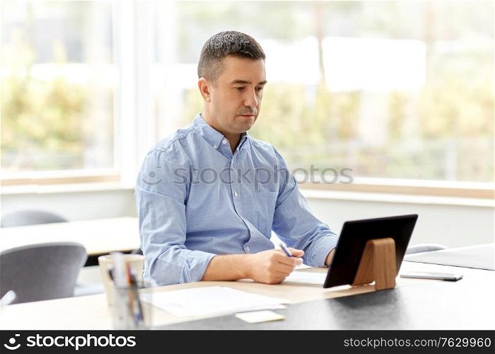 remote job, business and people concept - middle-aged man with tablet pc computer working at home office. man with tablet computer working at home office