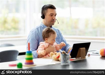 remote job, multi-tasking and family concept - middle-aged father in headset with baby working on tablet pc computer at home office. father in headset working at home office with baby