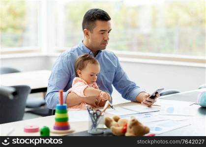 remote job, multi-tasking and family concept - middle-aged father with baby and smartphone working at home office. father with baby and smartphone working at home