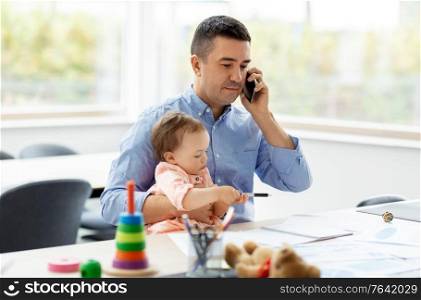 remote job, multi-tasking and family concept - middle-aged father with baby calling on smartphone at home office. father with baby calling on phone at home office