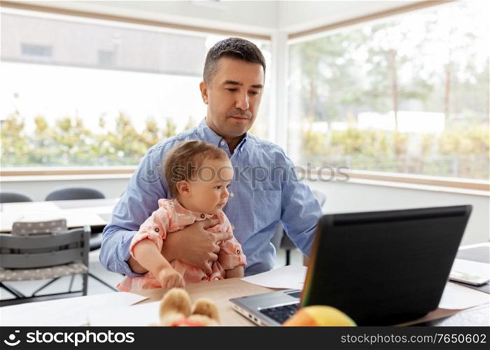 remote job, multi-tasking and family concept - middle-aged father with baby daughter working on laptop at home office. father with baby working on laptop at home office