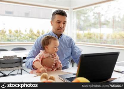 remote job, multi-tasking and family concept - middle-aged father with baby daughter working on laptop at home office. father with baby working on laptop at home office