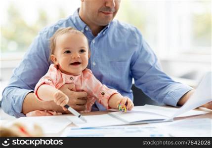 remote job, multi-tasking and family concept - middle-aged father with baby working at home office. father with baby working at home office