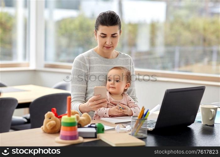 remote job, multi-tasking and family concept - mother with baby, smartphone and laptop working at home office. mother with baby and phone working at home office